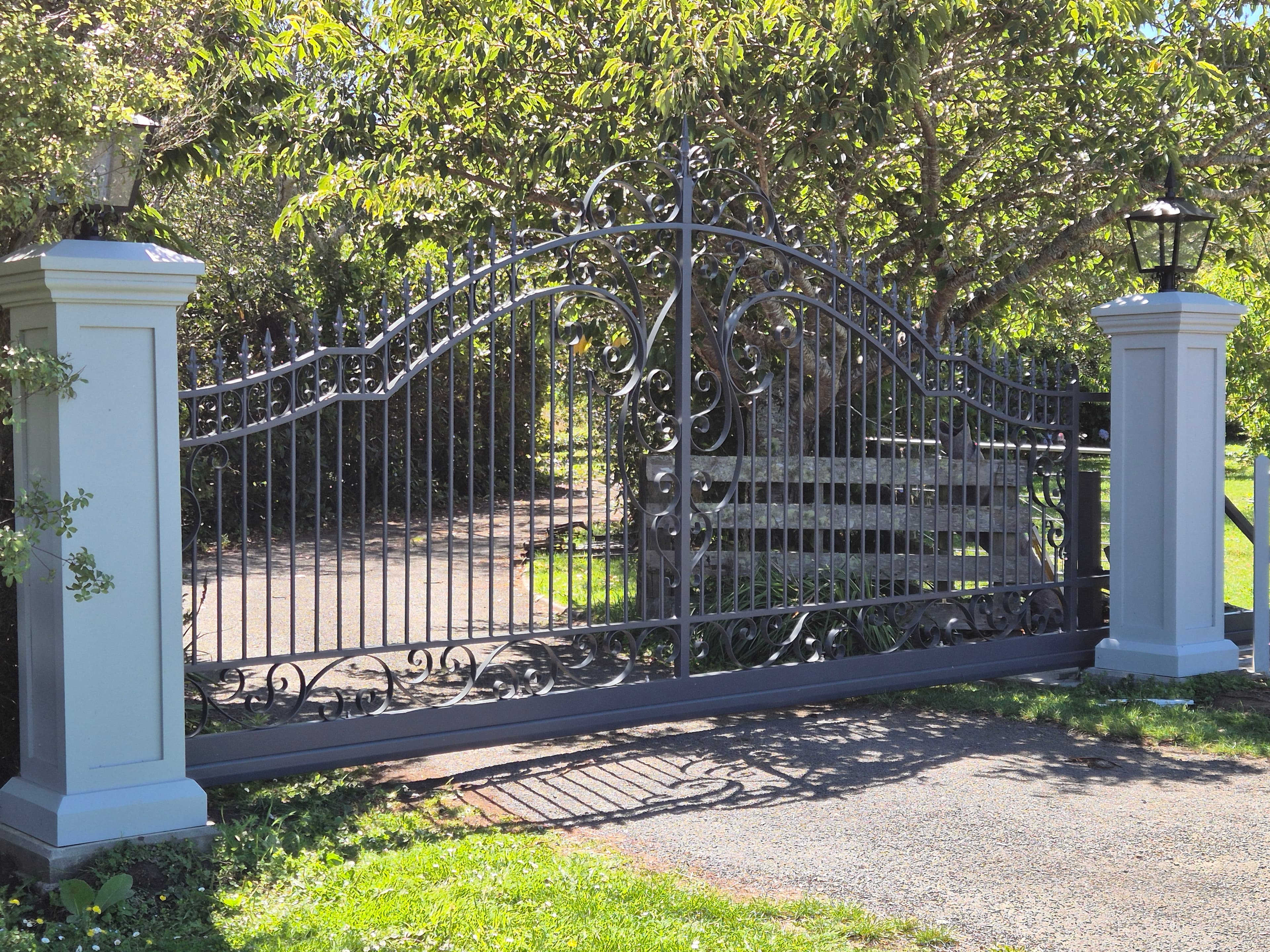 Grand ornate iron entrance gate flanked by brick pillars